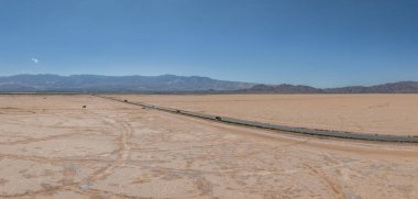 Amerika 'nın güneybatısının çorak manzarası boyunca uzanan sonsuz düz yolun klasik manzara manzarası. Yazın mavi gökyüzü ve güneşli güzel bir günde aşırı sıcak sis.