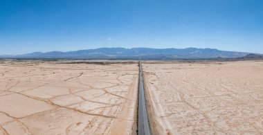 Amerika 'nın güneybatısının çorak manzarası boyunca uzanan sonsuz düz yolun klasik manzara manzarası. Yazın mavi gökyüzü ve güneşli güzel bir günde aşırı sıcak sis.