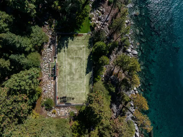 A birds eye view of a tennis court surrounded byforest. Tahoe lake nature in the USA.