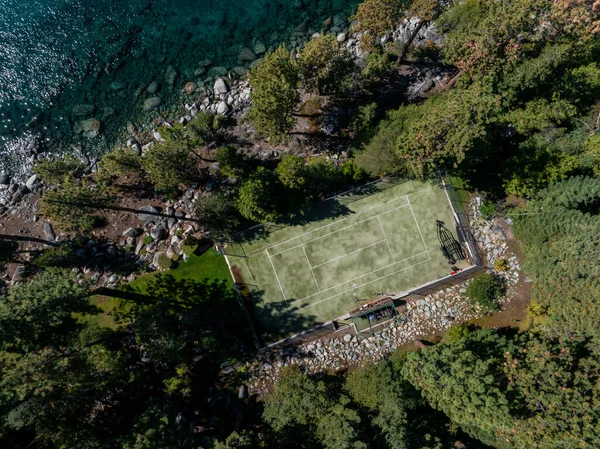 A birds eye view of a tennis court surrounded byforest. Tahoe lake nature in the USA.