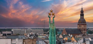 Özgürlük heykelinin yanında Riga 'nın üzerinde güzel bir gün doğumu manzarası var Letonya' da Milda. Özgürlük Anıtı.