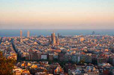 Barselona 'nın panoramik manzarası, Sagrada Familia' nın merkez sahnesiyle, Eixample semtleri şebeke sokakları ve modern ve tarihi mimarinin bir karışımı ile çevrili..