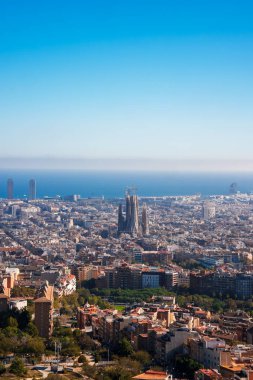 Açık mavi gökyüzü altında Sagrada Familia 'nın yer aldığı Barcelonas şehir manzarasının panoramik manzarası, Akdeniz ve modern mimarinin arka planda yer aldığı.