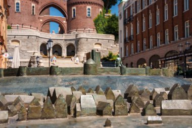 Ön planda hareketsiz bir çeşme ve bulanık bir arka planda kemerli kırmızı tuğlalı bir bina, açık mavi bir gökyüzü ve Helsingborg 'da yakınlardaki kafelerin ipuçlarına sahip bir şehir manzarası..