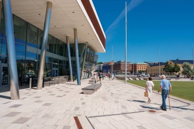 Geniş bir yürüyüş yolu, modern binalar ve Helsingborg 'da uysal insanlar olan güneşli bir şehir. Mavi bir gökyüzü, çeşitli kaldırımlar, cam ve ahşap süslemeli yapılar var..