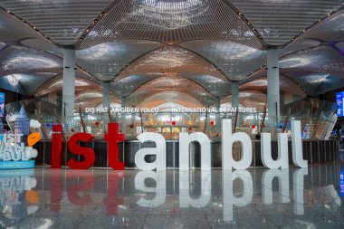 İstanbul Havalimanı 'nda, Türk bayrağı renklerinde canlı bir İstanbul tesisi göze çarpıyor. Bölge, pek çok ışığın aydınlattığı fütüristik ve dalgalı bir tavan altında Uluslararası Kalkış 'a öncülük ediyor..