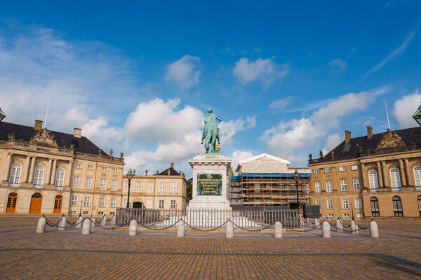Спокойная, пустая общественная площадь в Копенгагене, с центральной конной статуей, классическими европейскими зданиями с мансардными крышами и продолжающимися реставрационными работами.