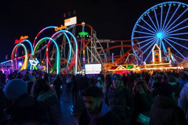 Londra 'da canlı bir Noel panayırı. Geniş mavi dönme dolap, renkli kemerler ve kış kıyafetleri giymiş neşeli bir kalabalık. Geceleri eğleniyorlar..