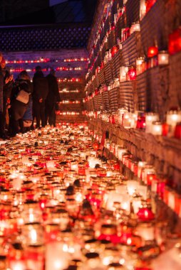 Letonya 'da kutsal bir toplantı. Kırmızı tutucularda küçük mumlar, birlik ve hatıraları simgeliyor. Sıcak giysili insanlar Bağımsızlık Günü için bir dakikalık saygı duruşunda bulunuyorlar..