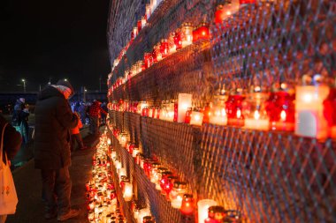 Her yaştan insanın loş ve yansıtıcı bir törenle bir araya geldiği Latvias Bağımsızlık Günü anısına, kırmızı ve beyaz renkli mumlar bir çit boyunca yanıp sönüyor..