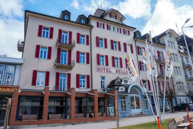 Engelberg 'de çok katlı klasik bir Avrupa tasarımı olan şık bir otel. Ön cephe, kırmızı panjurlar ve zemin kat kafesi var. Bayraklar temiz bir gökyüzü altında uluslararası yetenek ekler.