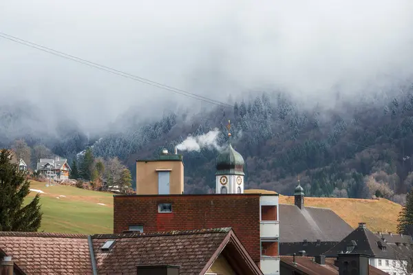エンゲルベルクの山村の風景 時計塔 煙突からの煙 霧林の斜面 スキーシーズンの前に穏やかで寒い雰囲気を示唆する — ストック写真