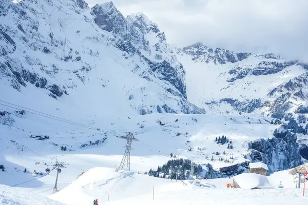 スイスのエンゲルベルクは 成長した斜面 作業スキーリフト 雪に覆われた高山の頂上にスキーヤーを誇り 渓谷のリゾートアメニティを備えています — ストック写真