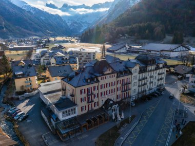 Engelberg tatil beldesinin hava görüntüsü, belirgin HOTEL BELLEVUE ve kırmızı beyaz cephesi. Yakınlarda, temiz sokaklar ve dağ tarzı binalar görkemli, karlı zirvelerin olduğu bir zemin üzerine kurulmuş..