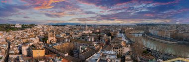 An aerial view of Rome at dusk reveals a vibrant sky in orange, pink, purple, and blue. Ancient and modern buildings, terracotta roofs, and church domes stand out. The Tiber River enhances the scene. clipart