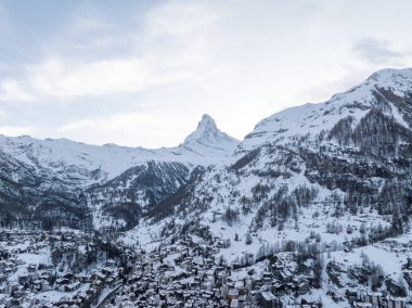 A stunning aerial shot of Zermatt in the Swiss Alps, with the snow capped Matterhorn. Its alpine buildings and calm, wintry scene offer a charming vibe for winter sports fans and nature admirers. clipart