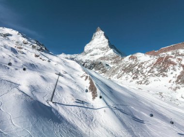 İsviçre, Zermatt 'ın hava görüntüsü, teleferikli Matterhorn ve kayak yamaçlarını gösteriyor. Mavi gökyüzü ve taze raylar kış sporlarının cazibesinin altını çiziyor.