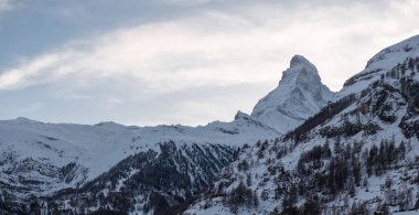 İsviçre, Zermatt 'ın havadan çekilmiş görüntüleri, kar çatısı olan dağ evleri ve otelleri gösteriyor. Matterhorn zirvesi göze çarpıyor. Karlı yamaçlara ve dağlara doğru dönen bir çarklı demiryolu var..