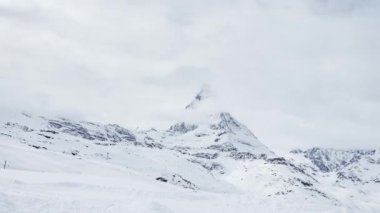 Güneşli bir günde, karlı Matterhorn zirvesinin manzarası. Mavi gökyüzü ve arka planda biraz bulut, İsviçre.