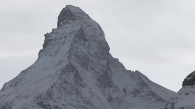 Güneşli bir günde, karlı Matterhorn zirvesinin manzarası. Mavi gökyüzü ve arka planda biraz bulut, İsviçre.