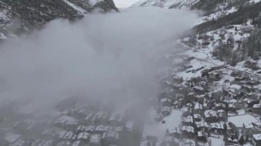 İsviçre 'de sakin bir Alpler kayak merkezi olan Zermatt' ın hava görüntülerinde kar altında kiraz ve modern tesisler sergileniyor. Matterhorn ve karla kaplı tepeler ardında süzülüyor, sakin, görkemli bir kış cenneti yaratıyor..