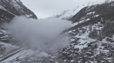 İsviçre 'de sakin bir Alpler kayak merkezi olan Zermatt' ın hava görüntülerinde kar altında kiraz ve modern tesisler sergileniyor. Matterhorn ve karla kaplı tepeler ardında süzülüyor, sakin, görkemli bir kış cenneti yaratıyor..