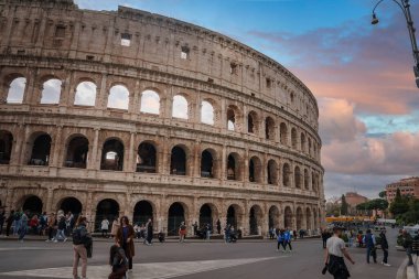 Roma 'da tarihi kolezyum, İtalya' da kemerler, duvar, turistler, şehir sokağı, sarı otobüs, trafik ışıkları, lamba direkleri. Eski ve yeninin ikonik amfitiyatroda karışımı.