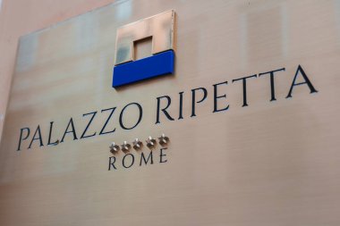 Roma 'daki Palazzo Ripetta tabelasının yakın görüntüsü. Fırçalanmış metal arka plan, cilalı harfler, zarif yazı tipi, mavi logo. Şehirdeki lüks oteli gösteriyor..