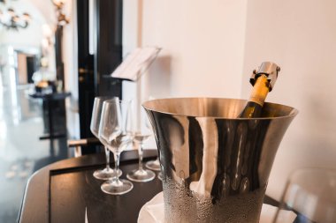 Buz kovasında şampanya şişesi, iki şarap bardağı, arka planda zarif iç dekorasyon. Lüks otel havası. Roma 'nın yeri. Lüks ve boş zaman ortamı.