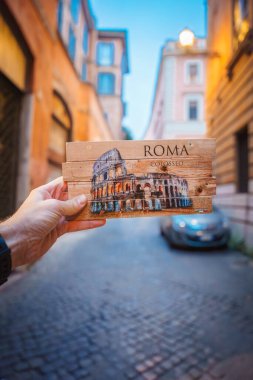 Roma 'daki Colosseum kartpostalı, sokak perspektifiyle mükemmel hizalanır ve büyüleyici bir görsel etki yaratır. Roma kaldırım taşı sokağında güneşli bir akşam.