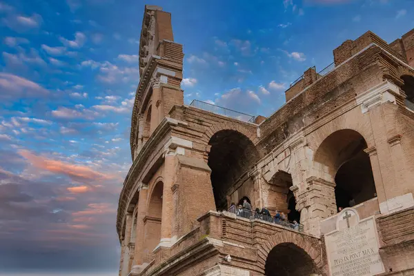 Roma, İtalya 'daki ikonik Colosseum' u keşfedin. Bulutlu bir gökyüzünün altındaki antik mimariye bakın, ziyaretçiler yüksek görüş noktalarından etkileyici harabelere hayran kalıyorlar..