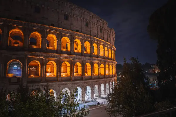 Kolezyum, İtalya, Roma 'daki Flavian Amfitiyatrosu, gece çekilmiş. Ilık ışıkla aydınlatılmış, büyük mimarisi ve karmaşık ayrıntıları vurgulanmış. Sakin, görkemli bir atmosfer..