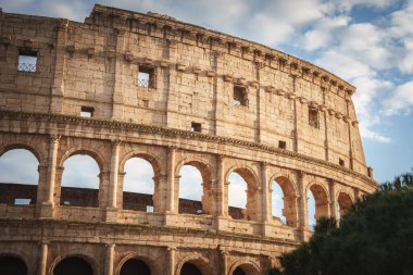 Roma, İtalya 'daki Flavian Amfitiyatrosu olarak da bilinen ikonik Colosseum' a yakından bakın. Parçalı bulutlu bir gökyüzünün altında kemerleri ve eski taşları renklendiriyor.