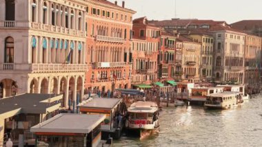 Venedikli gondolcu Venedik İtalya 'nın yeşil kanal sularında gondola biniyor. Ünlü Canal Grande 'deki geleneksel Gondol manzarası gün batımında romantik altın bir akşam ışığı altında.