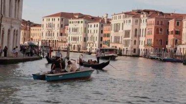 Venedikli gondolcu Venedik İtalya 'nın yeşil kanal sularında gondola biniyor. Ünlü Canal Grande 'deki geleneksel Gondol manzarası gün batımında romantik altın bir akşam ışığı altında.