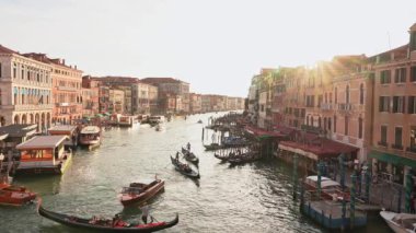 Venedikli gondolcu Venedik İtalya 'nın yeşil kanal sularında gondola biniyor. Ünlü Canal Grande 'deki geleneksel Gondol manzarası gün batımında romantik altın bir akşam ışığı altında.