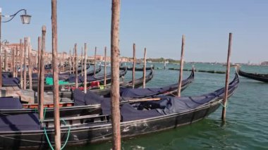 Venedik geleneksel gondolları Büyük Kanal 'daki tahta demirleme direkleriyle kenetlenmiş Santa Maria Della Salute, Venedik, İtalya.