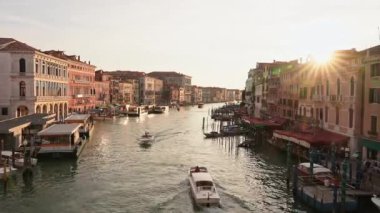 Venedikli gondolcu Venedik İtalya 'nın yeşil kanal sularında gondola biniyor. Ünlü Canal Grande 'deki geleneksel Gondol manzarası gün batımında romantik altın bir akşam ışığı altında.