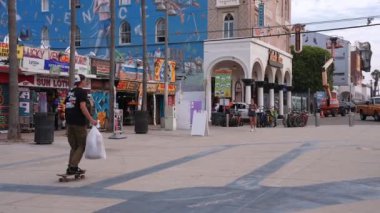 Venice plaj bölgesindeki palmiye ağaçları ve binaların oradaki insanlar. Venedik plaj ruhu. Renkli binalar, tabelalar ve insanlar koşup paten kayıyor..