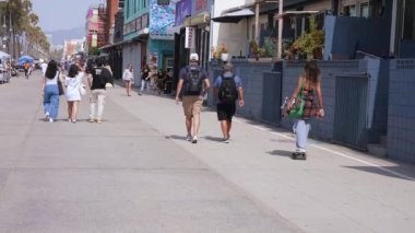 Venice plaj bölgesindeki palmiye ağaçları ve binaların oradaki insanlar. Venedik plaj ruhu. Renkli binalar, tabelalar ve insanlar koşup paten kayıyor..