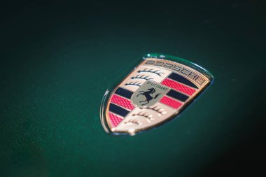 Almanya 'nın Stuttgart kentindeki Porsche ambleminin tam ortasında. Koyu yeşil arka plana karşı ayrıntılı tasarım. Bulanık odak metalik parlaklığı vurguluyor.