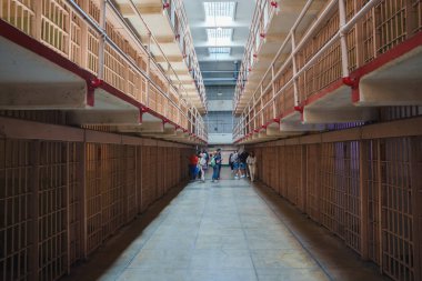 San Francisco, ABD 'deki Alcatraz hapishanesinin iç manzarası. İki katlı hücreli uzun koridor, parmaklıklı kapılar, kırmızı tırabzanlar. Ziyaretçiler rehberli tur, tarihi atmosfer.