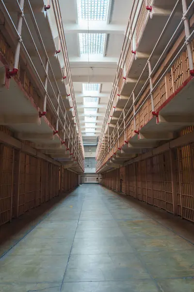 Alcatraz hapishanesinin iç manzarası, San Francisco, ABD. Parmaklıklı kapıları, kırmızı boruları, aşınmış yeşil beton zemini ve doğal ışık pencereleri olan hücre bloğunun zemin seviyesi..