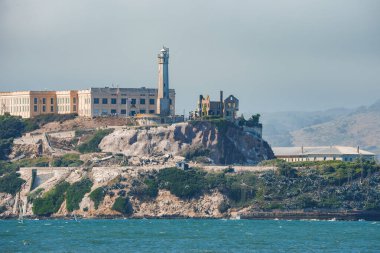Amerika 'nın San Francisco Körfezi' ndeki Alcatraz Adası 'nın uzak bir manzarası. Meşhur eski Alcatraz Federal Cezaevi' yle tanınıyor. Rocky arazisi, deniz feneri ve deniz aktiviteleri.