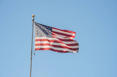 San Francisco 'da mavi gökyüzünde dalgalanan ikonik Amerikan bayrağı. Sembolik 50 yıldız ve 13 çizgili tasarım, vatansever, turist veya simge kavramları için mükemmel.