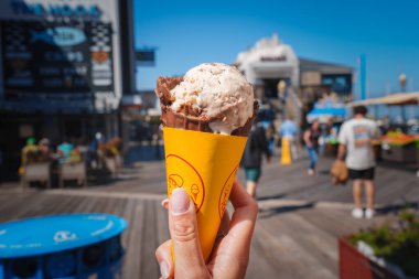 San Francisco 'daki Pier 39' da gülen yüzlü insanların elinde çikolatalı kurabiye hamurlu dondurma var. Kalabalık güneşli bir açık hava sahnesi.