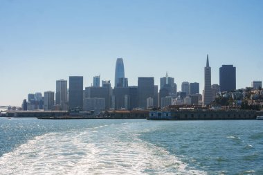 Daytime view of San Francisco skyline from the water, showing iconic buildings like Transamerica Pyramid and Salesforce Tower. Serene waterfront scene under clear blue sky. clipart