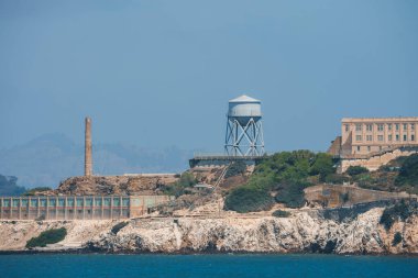 San Francisco Körfezi 'ndeki uzak Alcatraz Adası manzarası engebeli arazi, tarihi yapılar, su kulesi ve hücre evi. Popüler turizm merkezi.