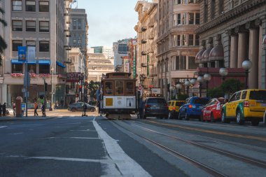 San Francisco 'da ikonik krem ve kestane renkli teleferik. Modern ve klasik mimarinin karışımı, kalabalık cadde araçlar ve yayalar, öğleden sonra atmosferi. Zengin geçmiş ve büyüme.
