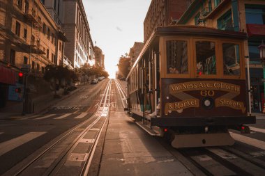 Iconic San Francisco cable car at Van Ness Ave. California St. and Market St. during golden hour. Classic architecture and hilly streets add charm. clipart